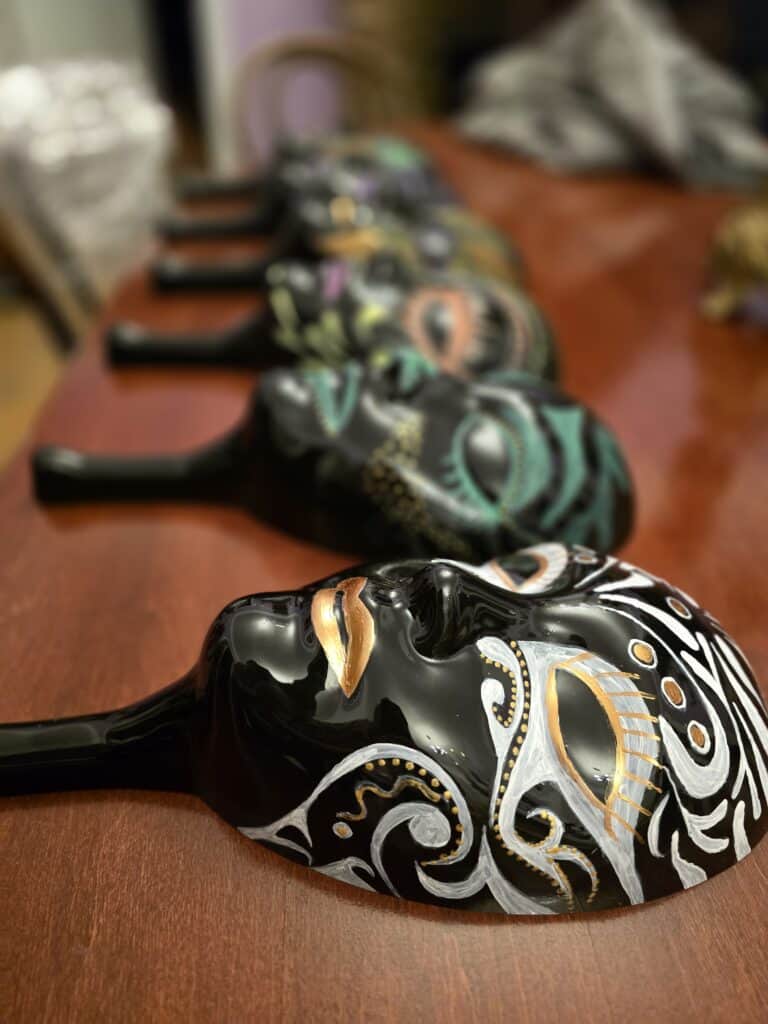 A row of colourful and decorated masks, symbolising the themes of the mafia and parliament.