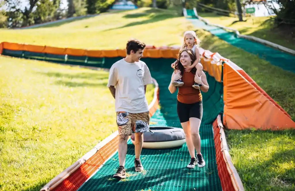 A family walks through an amusement park with a child and parents on a sunny day.
