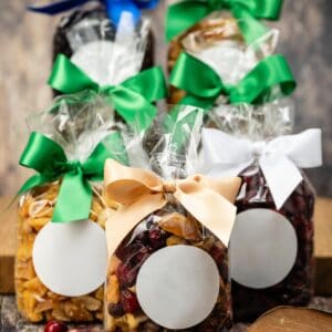 Nahrin dāvanu iepakojumi ar riekstiem, ogām un saldumiem, skaisti sapakoti ar krāsainām lentēm.