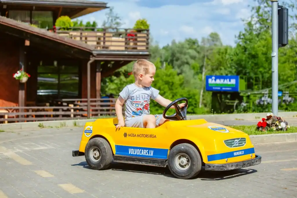 Children's electric car with blue and yellow paint, child in the driver's seat.