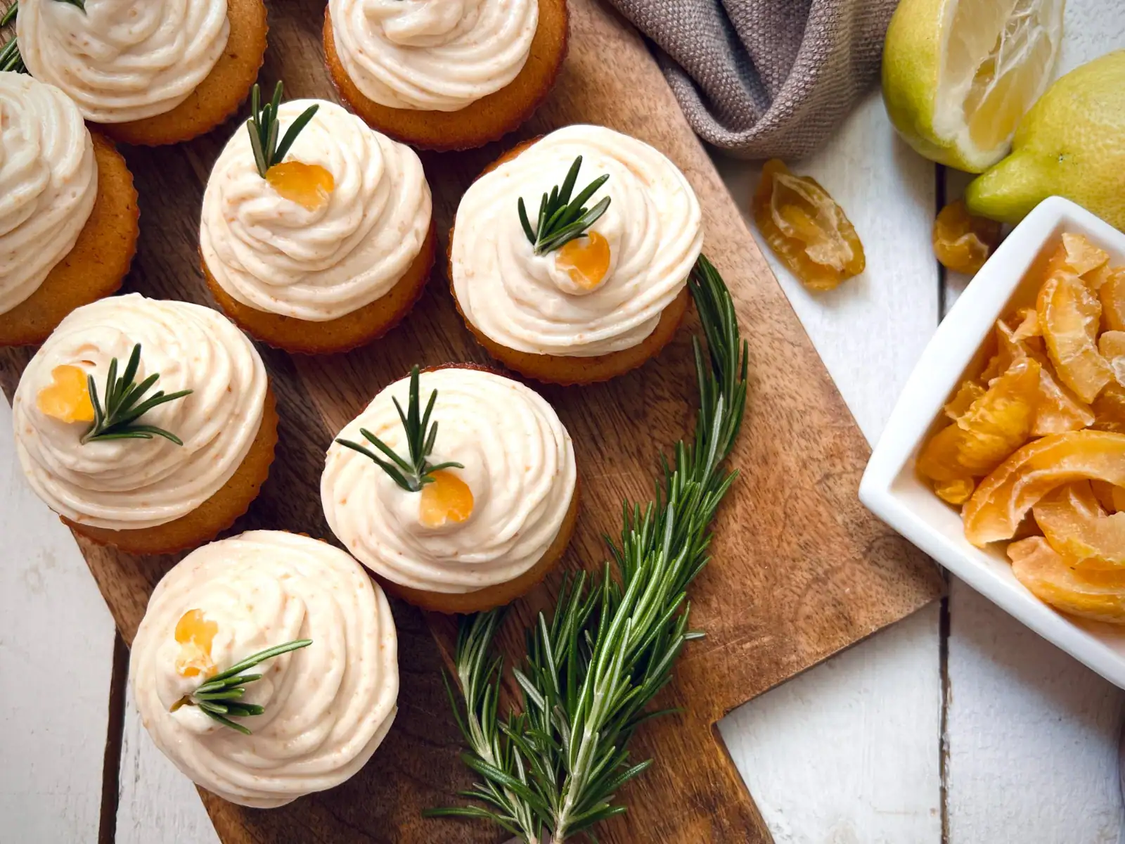 Quince cupcakes with cream cheese frosting, candied fruit and a rosemary garnish