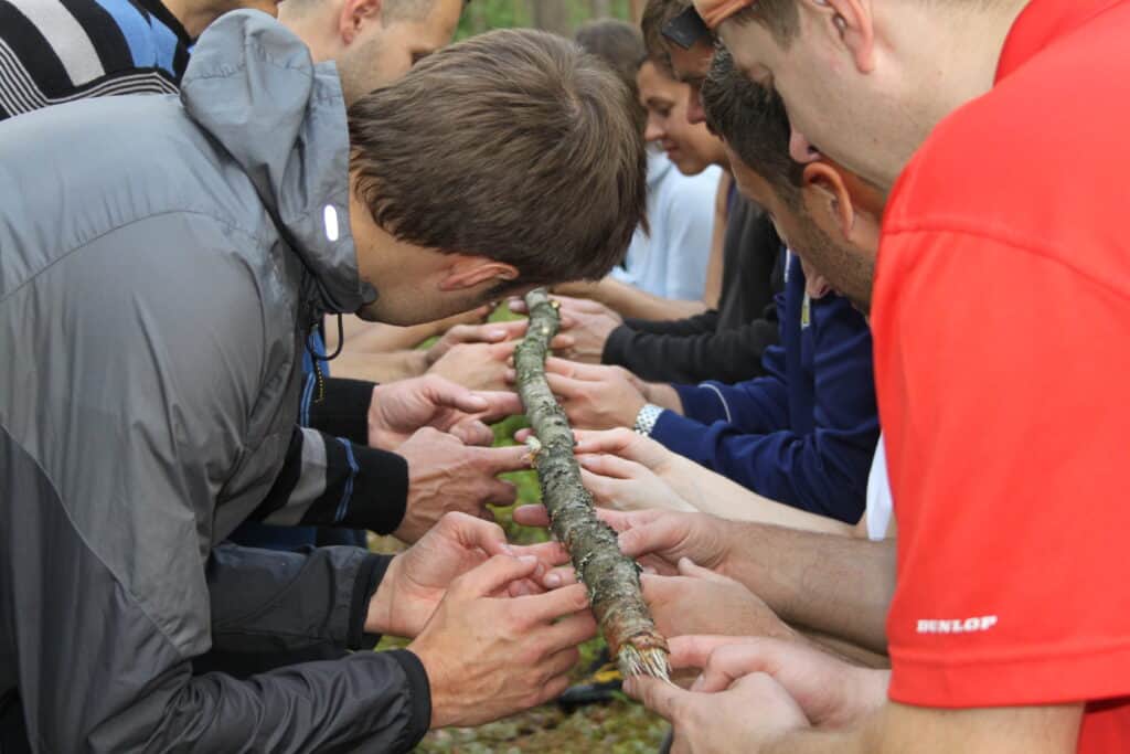 Groups of people holding the trunk of a tree, an educational activity.