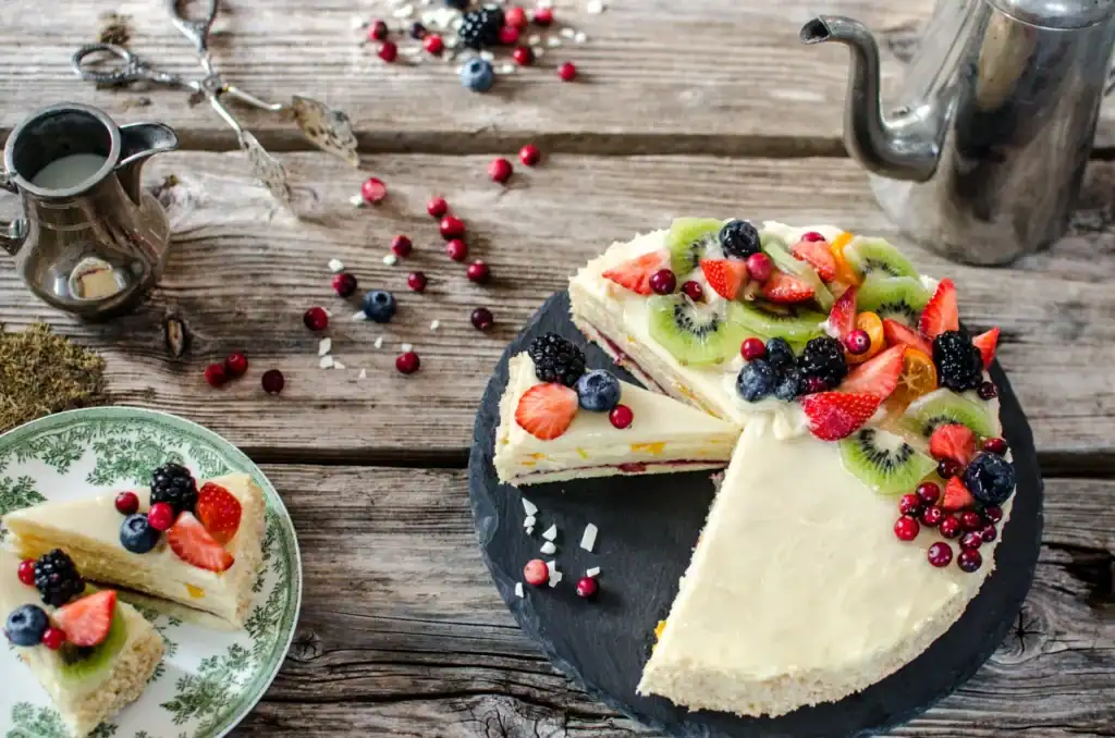 Fruit cake with fresh fruit, decorated with strawberries, blueberries and kiwi.