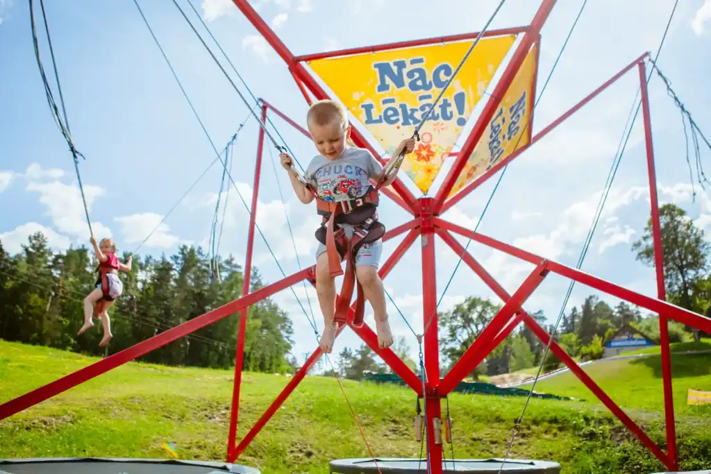 A child plays on a fun rubber with a blue sky and green grass background.