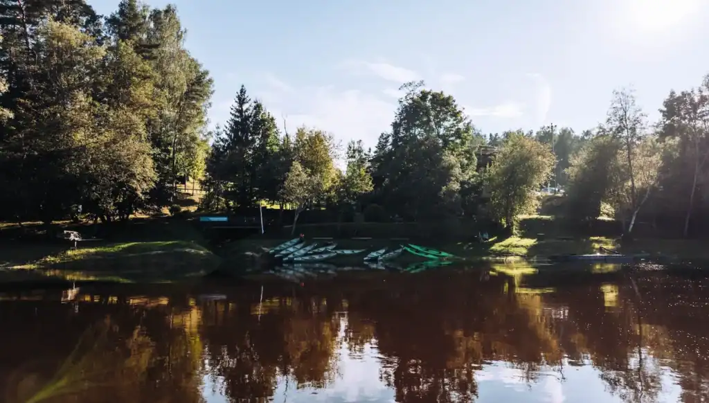 Ramkalni Natural landscape by the river with trees and grass, calm water surface.