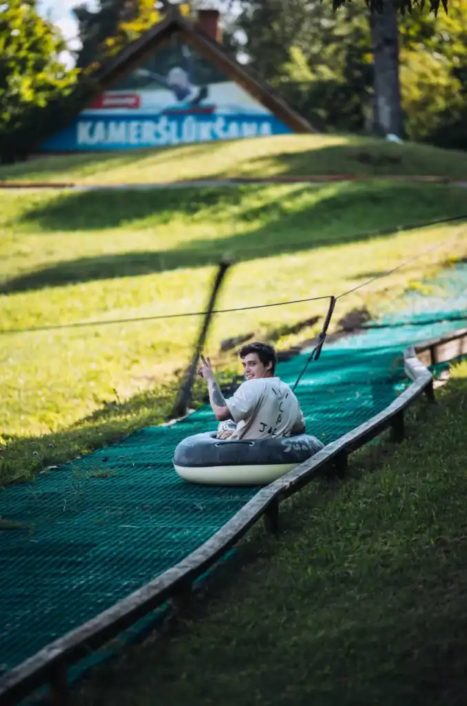A young boy reads a book on a slide in a green park, summer day.