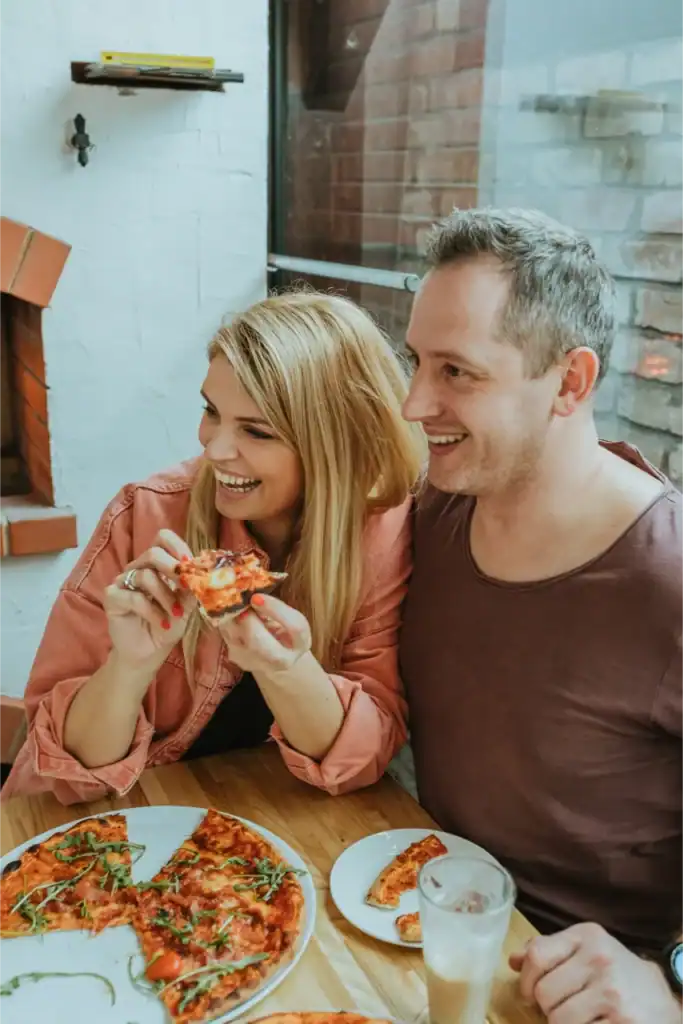 Two people enjoying pizza in a restaurant, friendly atmosphere, Ramkalni.