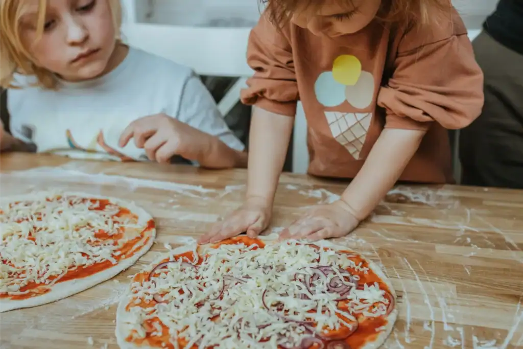 Children make and decorate pizzas with cheese and onions, a creative activity for children.