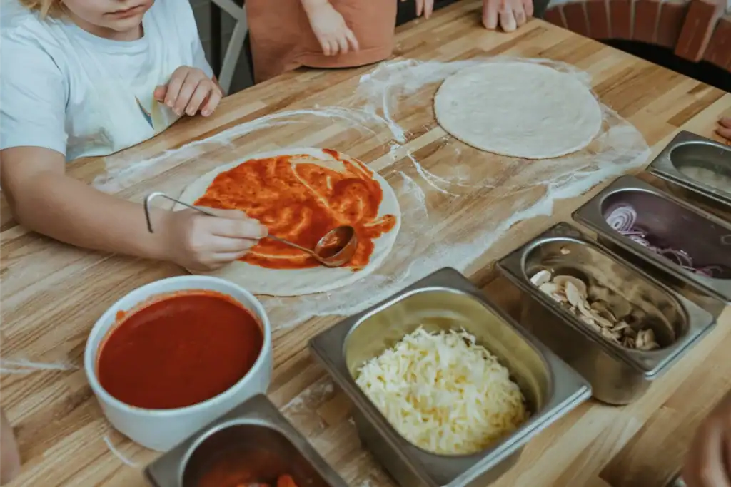 The children are making pizza dough using the ingredients and utensils.