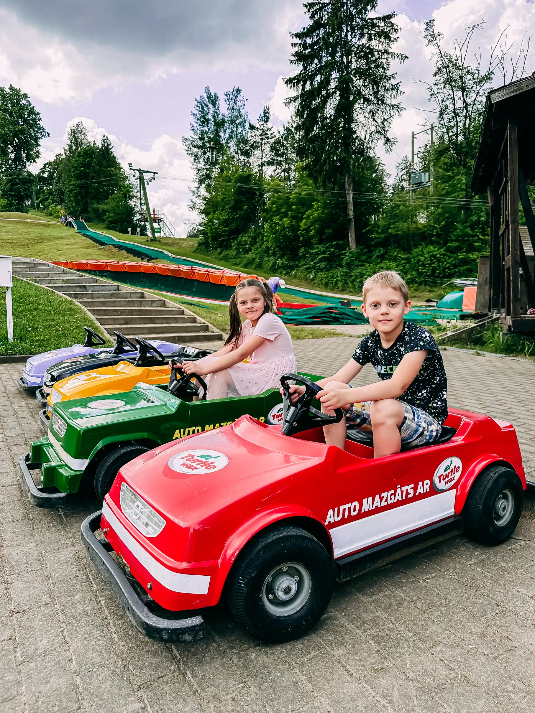 Children are playing with electric cars near Ramkalni Nature Park – family fun and leisure.