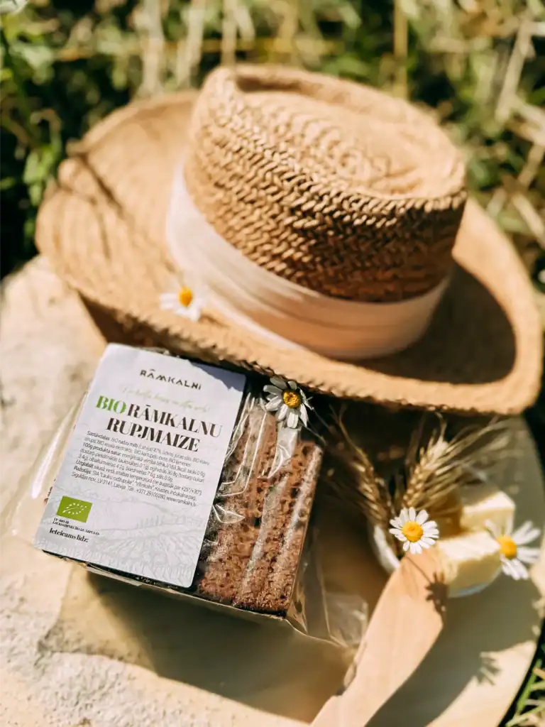 Rāmkalni organic produce, biscuits and a summer hat with flowers, a natural countryside setting.