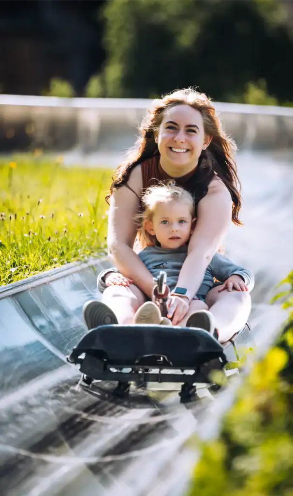 Healthy family fun with snowboards, a happy woman and a young child skiing down the hill.