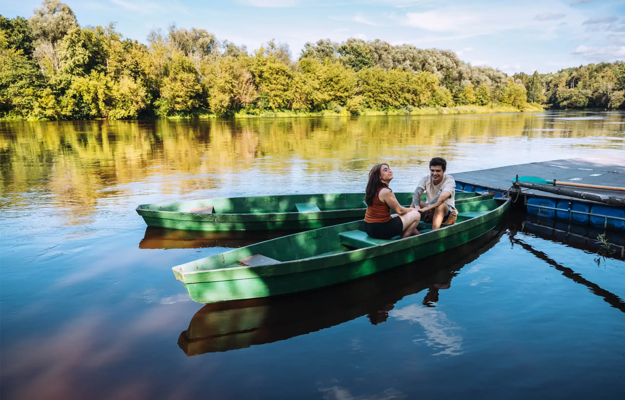 A boat trip down the river with two people, a natural landscape with green trees and calm water.