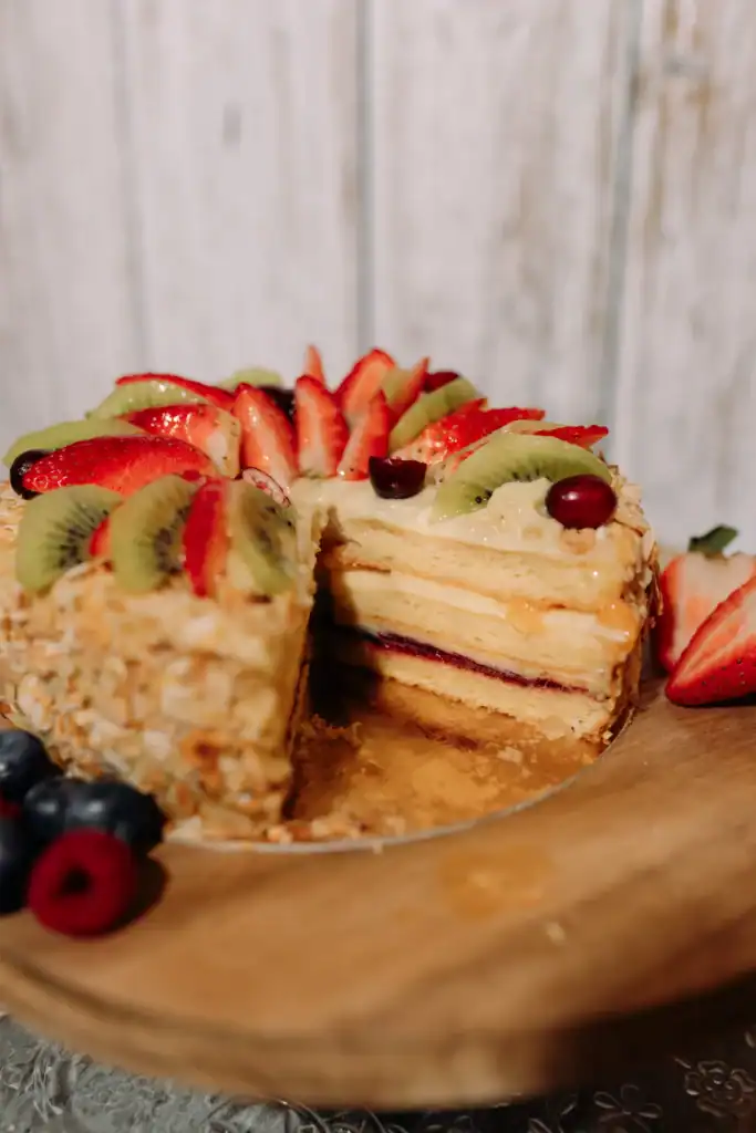 Cakes with fresh fruit, cream and layers of sponge, decorated with strawberries, kiwi and berries.