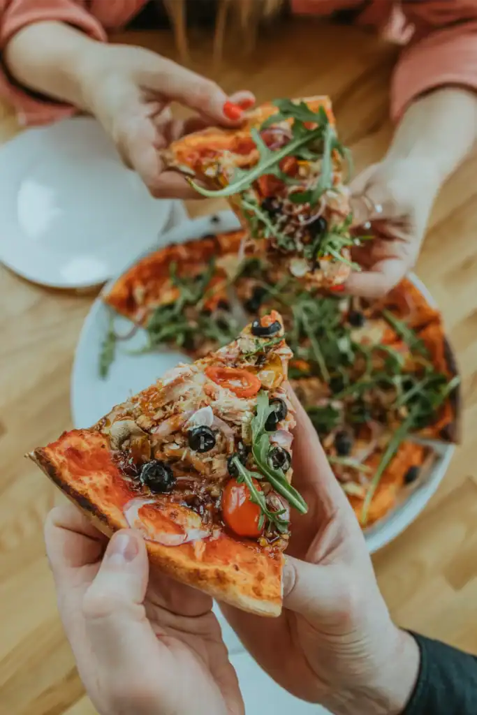 A slice of pizza with vegetables, olives and fresh herbs – the perfect snack.