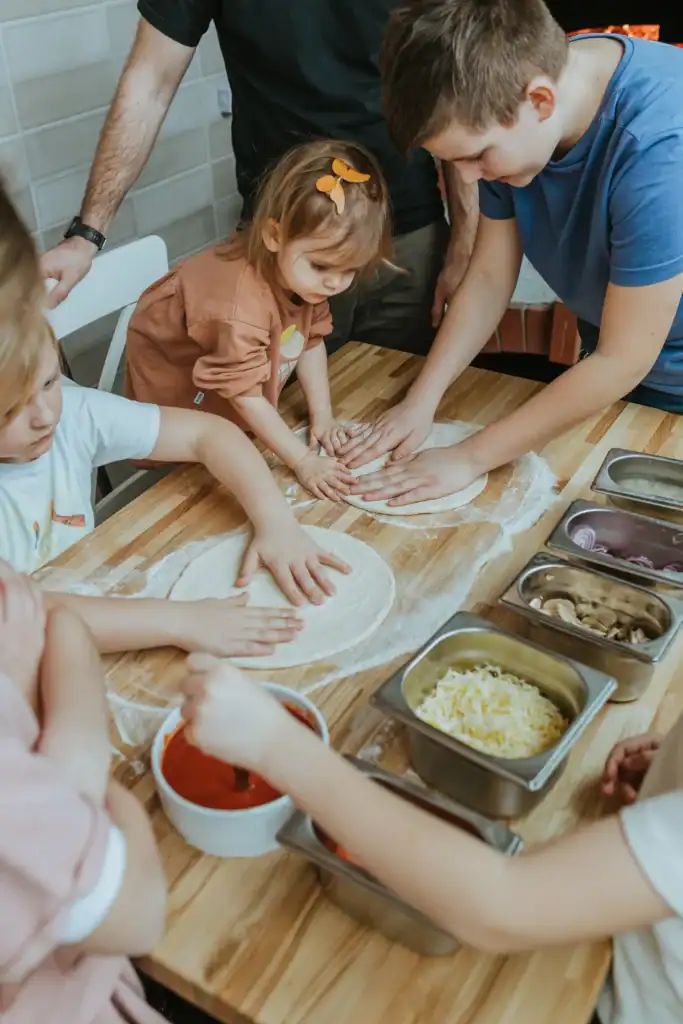 Children and adults make dough together in the kitchen – a creative family activity.