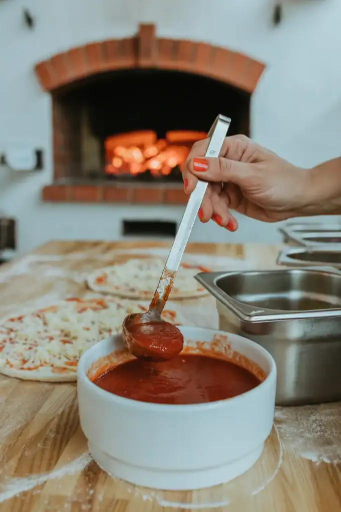 Farm work involving dough and tomato sauce, cooking in a wood-fired oven.
