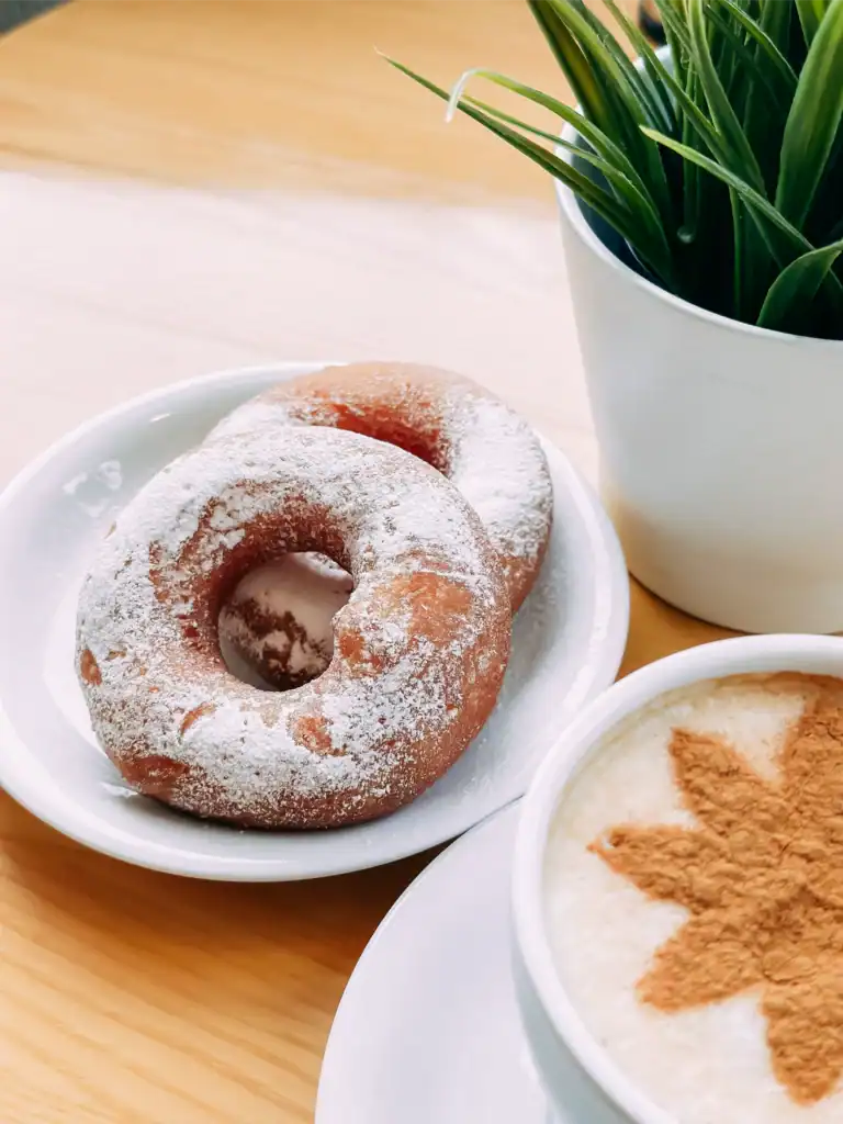 Candles dusted with icing sugar and a coffee drink, served together with a pot of green plants.