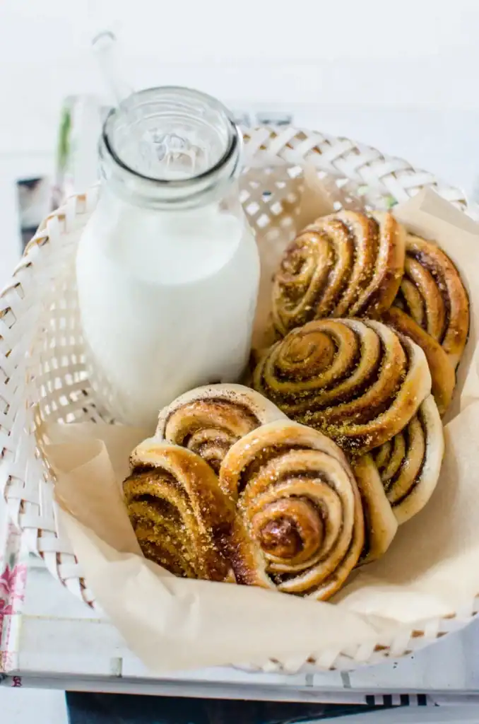 Sweet cinnamon and sugar spiral muffins with milk in a milk bottle.