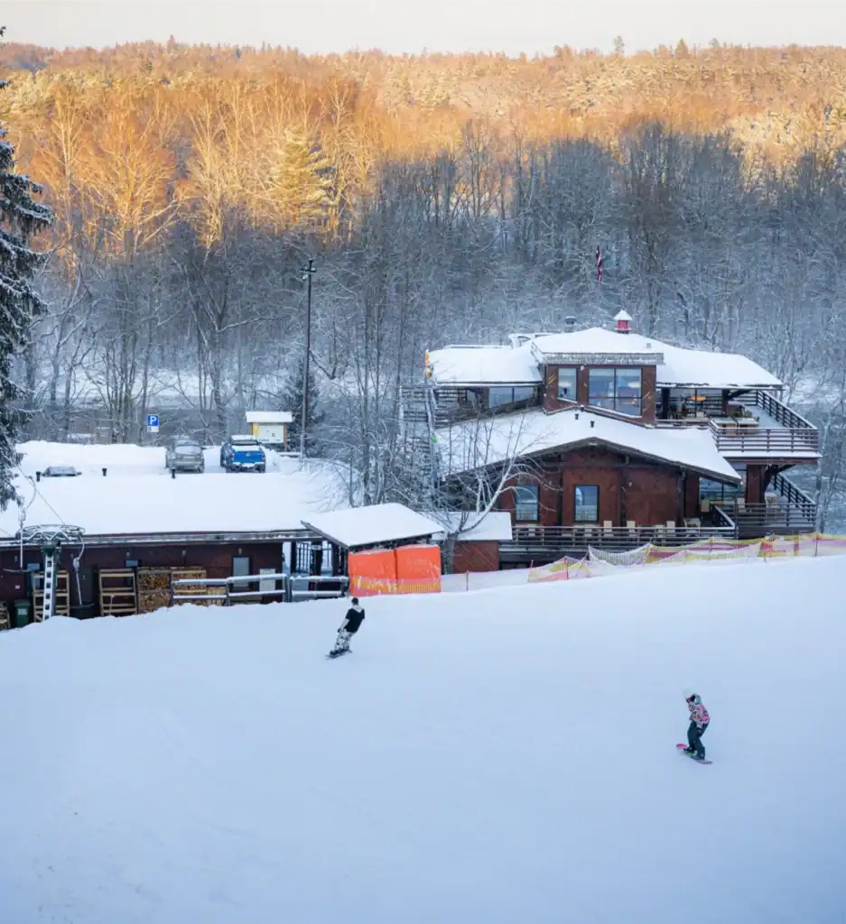 Clear winter landscape with houses and skiers, snow mountains, winter sports activities.