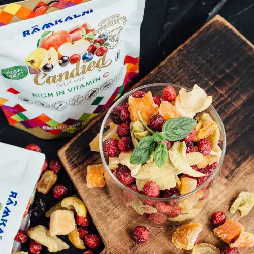 A bowl of healthy dried fruit and nuts, garnished with a green basil leaf.