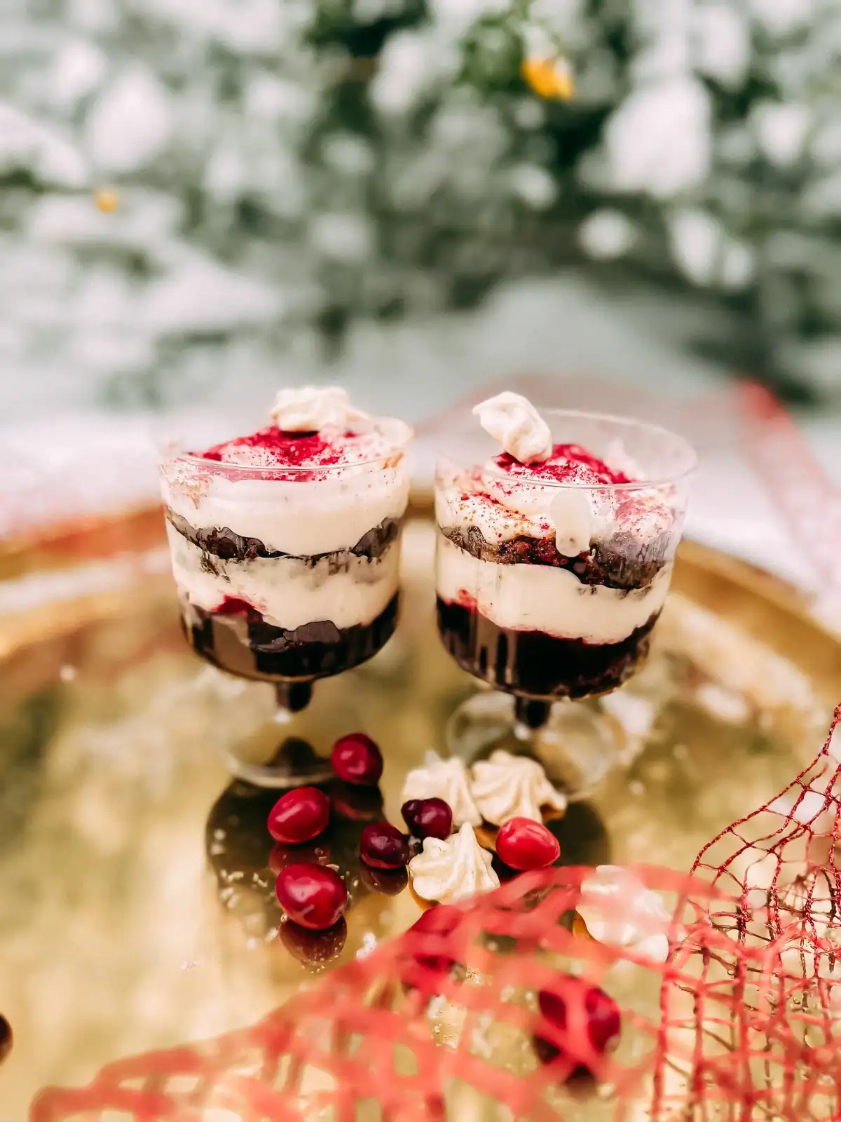 Two glasses layered with rye bread, a layer of cranberries and whipped cream